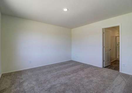 A spare bedroom in the Cottonwood floor plan with light brown carpet, white baseboards and white walls.