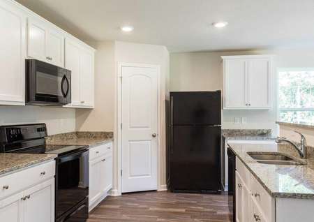 Avery floorplan kitchen with white cabinets and black appliances