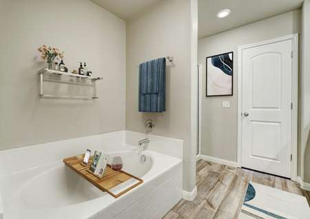Staged master bath with a large soaker tub, blue towel and separate shower.