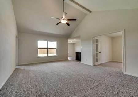Sabine new home plan family room with ceiling fan, brown carpeting, and glass French doors