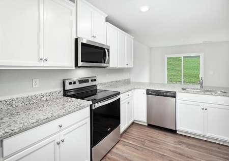 Kitchen with white cabinets, stainless steel appliances and luxury vinyl plank flooring.