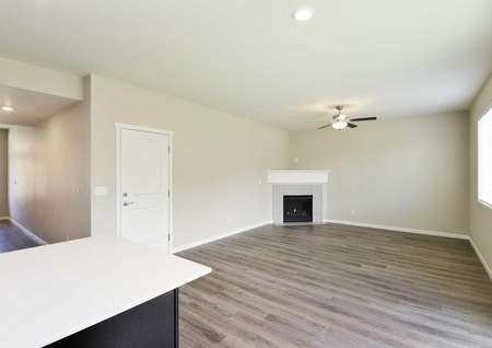 The Northwest Cypress living room is shown with vinyl wood like flooring and corner fireplace, lots of natural lighting.