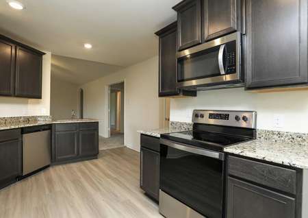 kitchen with granite, stainless electric range, built-in microwave, pale flooring looks into living room