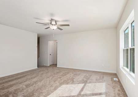 Photo of spacious living room with carpet and ceiling fan and window overlooking the back yard.