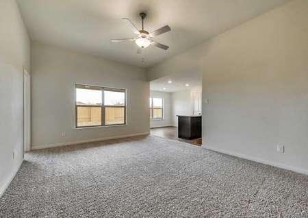 Large family room with soaring ceilings, a ceiling fan and quick access to the kitchen.