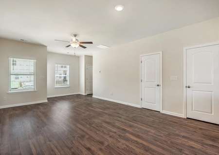 The spacious family room has wood-style flooring, great natural light and a ceiling fan.