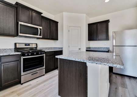 Upgraded kitchen with crown molding on the espresso cabinets and wood-style flooring throughout. 