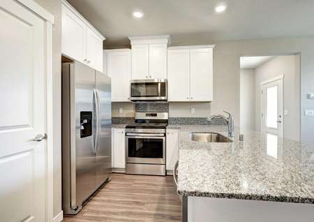 The Empire floor plan kitchen with wood-like flooring, stainless steel appliances and a pantry.