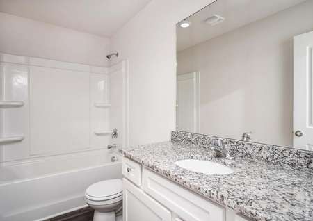 Secondary bathroom with white cabinetry.