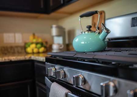 Model home kitchen completed with stainless steel modern stove with a turquoise color antique teapot sitting on top of it
