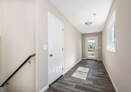 Photo of a spacious foyer with plank flooring, a coat closet and window.