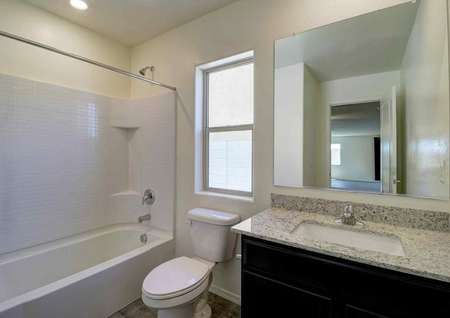A bathroom in the Guadalupe floor plan that has a sink, granite countertops and a bathtub/shower combo.