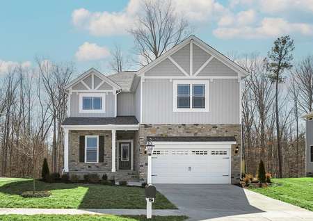 Photo of the front of the two-story Waverly plan by LGI Homes with light gray siding, white trim and beige cobblestone detail and a covered front porch.
