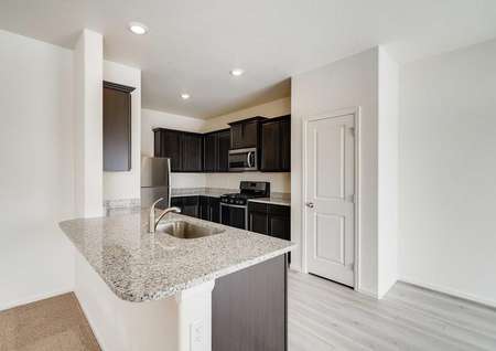 Kitchen sink, surrounded by granite countertops, with stainless steel appliances in the background. 