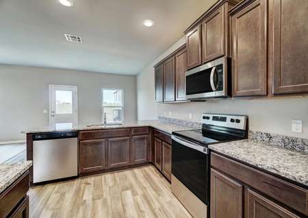 An open kitchen with beautiful cabinetry and granite countertops.