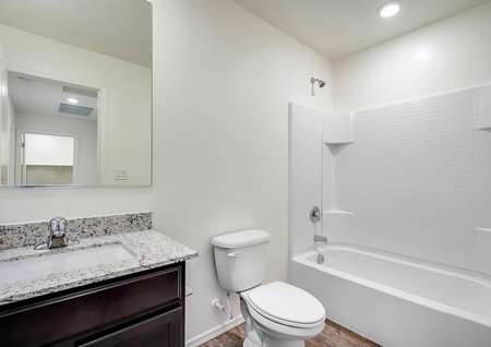 Secondary bathroom with a dual shower and bath tub, recessed lighting, and wood-style flooring.