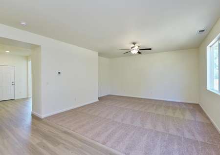 Spacious living room with carpet, ceiling fan and window to back yard.