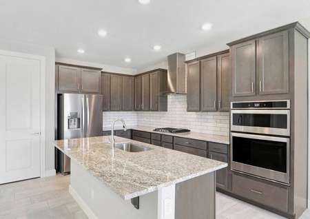 Bartlett kitchen with modern stainless steel appliances and hood, granite countertops, and large food prep island with sink