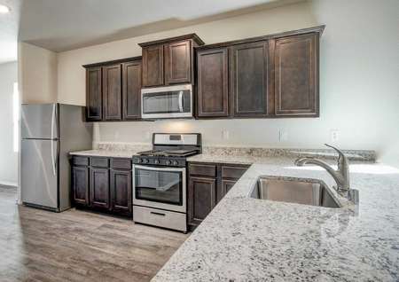 Bisbee kitchen with large granite counter, undermount sink, and dark brown cabinets