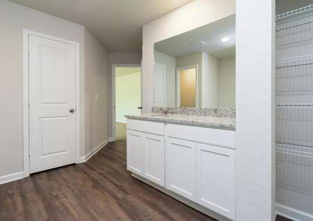 Master bathroom with granite countertops, white cabinets, and wood-style flooring.