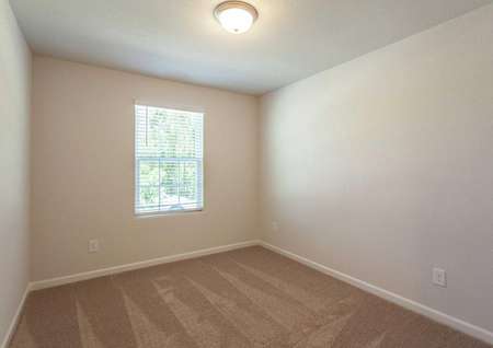 Alexander bedroom with window, off white walls, and brown carpeting
