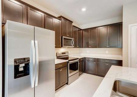 Fully upgraded kitchen in the Mateo model. Quartz countertops, stainless steel appliances, dark brown cabinetry and kitchen pantry