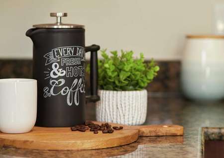 Coffee pitcher, cutting board, and coffee beans displayed on granite countertop in the kitchen. 