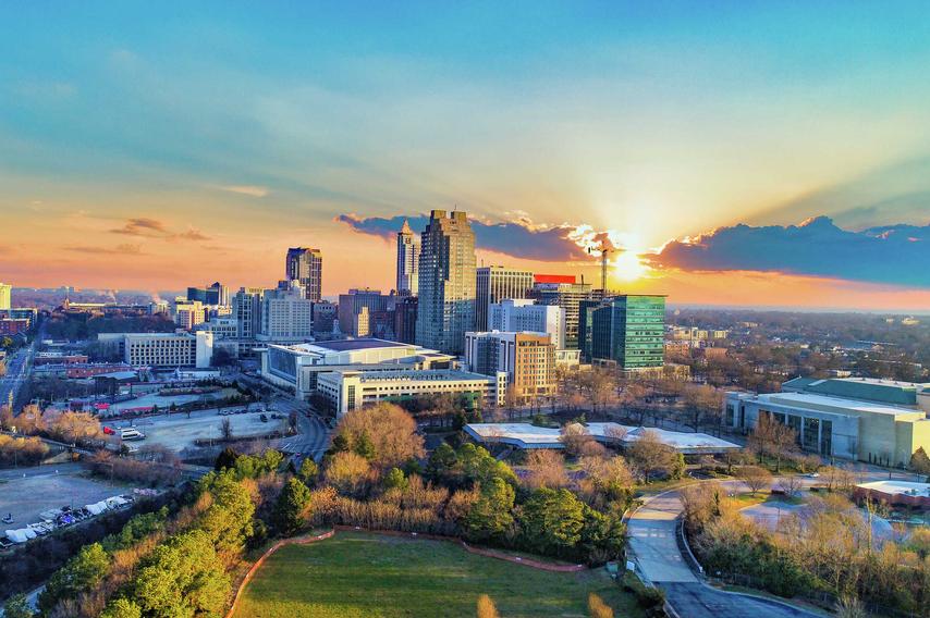 Raleigh, North Carolina downtown cityscape with large office buildings, parks, and other buildings at sunrise