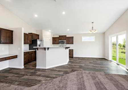 Photo of an open kitchen with brown cabinets, white counters, plank flooring and carpet.