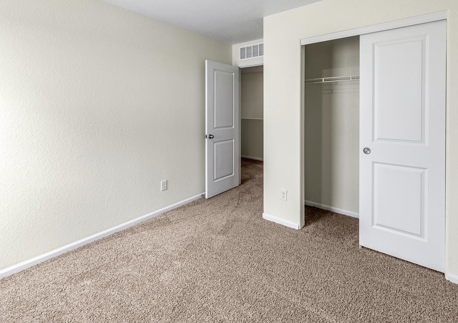 Secondary bedroom with tan carpet and a closet with sliding doors.