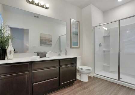 The master bathroom with white walls, brown cabinets and a walk-in shower in the Pine Key floor plan