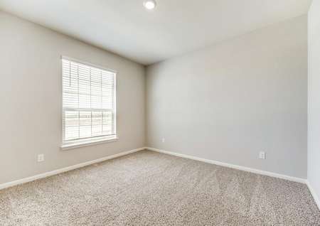 The secondary bedrooms offers a large window, tan walls and light brown carpet.