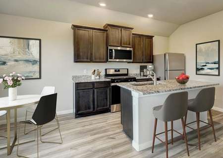 Staged kitchen with brown cabinetry and stainless steel appliances.