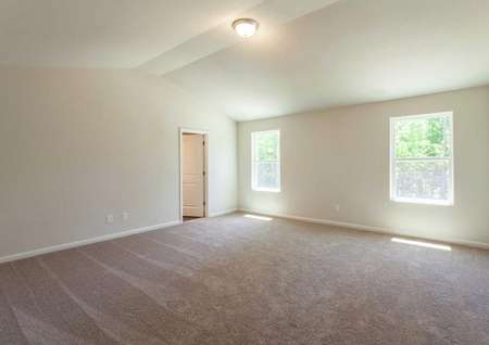 Fripp master bedroom with large windows, tan carpet, and vaulted ceilings