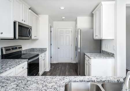 Kitchen with granite countertops, white cabinets and stainless steel appliances.