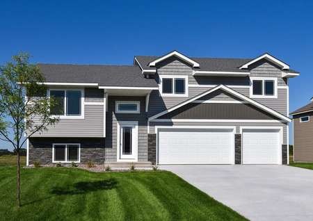 Front elevation photo of the St Mary by LGI Homes with light gray siding, dark gray water table stone and white trim.