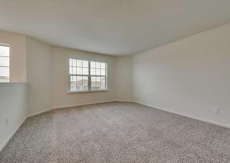 Game room in the Oakmont model with carpet flooring and large exterior window with 2