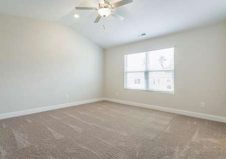 Master bedroom with carpet, a large window and a ceiling fan.