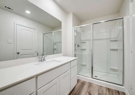 A full bathroom with a standing shower and white countertops.