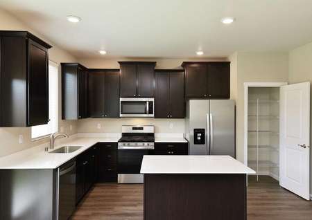 The Northwest Cypress kitchen offers another view showing an open pantry door and stainless steel appliances.