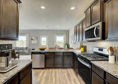 Staged kitchen with stainless steel appliances and brown cabinetry.
