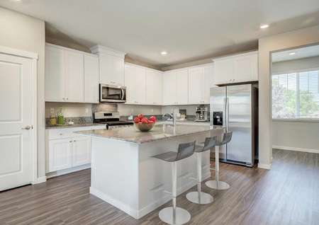 Fully furnished kitchen with white cabinets, granite countertops and breakfast bar in the Loomis floor plan.