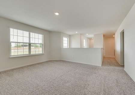 The upstairs area of this home has a game room with brown carpet and white walls.