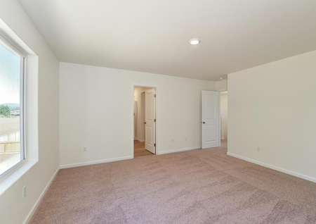Spacious upstairs master bedroom with carpet and large window and attached bathroom.