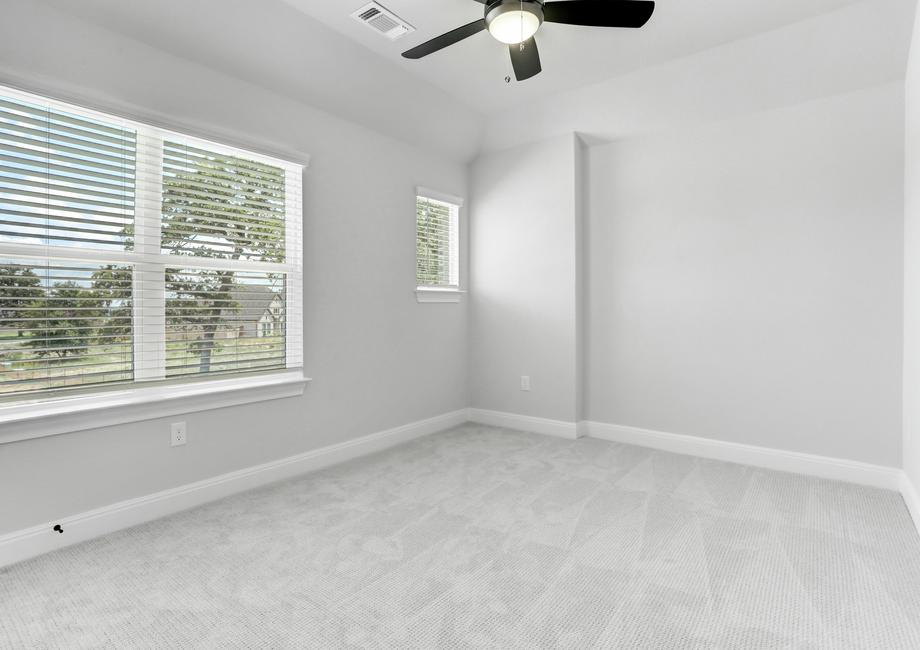 Guest bedroom with large windows, a ceiling fan, and gray carpet.
