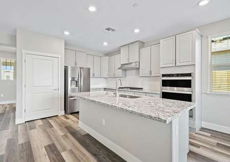 Stunning designer kitchen with a large granite island, stainless appliances, and white cabinets. 