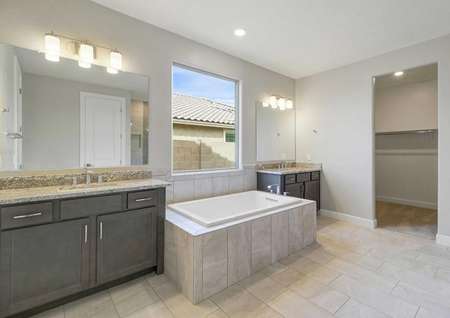 Hawley master bath with two granite vanities, brown cabinetry, and large framed-in bathtub