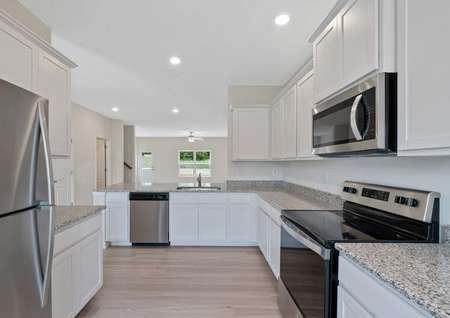 Spacious kitchen of the Potomac with white cabinets, stainless appliances, plank flooring, recessed lights, abundant storage.