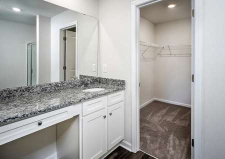 Master bathroom with large vanity, white cabinets, granite countertops and access to a walk-in closet. 