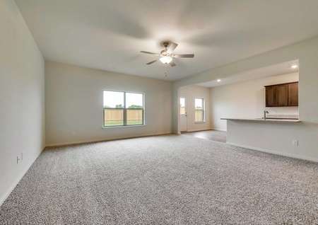 Oakmont model living room with carpet and ceiling fan, view of the open floor plan with kitchen in the background
